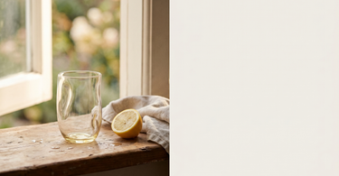 Klart drikkeglas fra Anna von Lipa på en vindueskarm med en halv citron