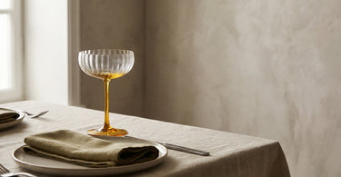 Ribbet champagneglas med gul stilk fra Anna von Lipa i en elegant kuvert med tallerken og serviet
