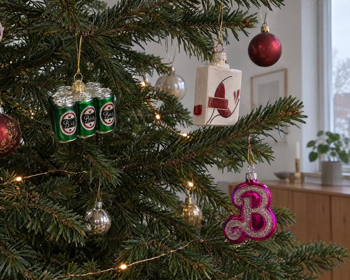 Sjove julekugler i glas formet som six-pack, papvin og et pink B på et juletræ